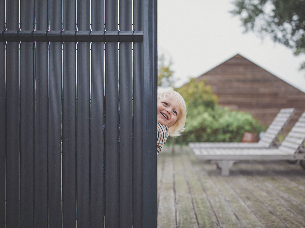 petite fille souriant à moitié cachée par un kit d'occultation sur panneau rigide